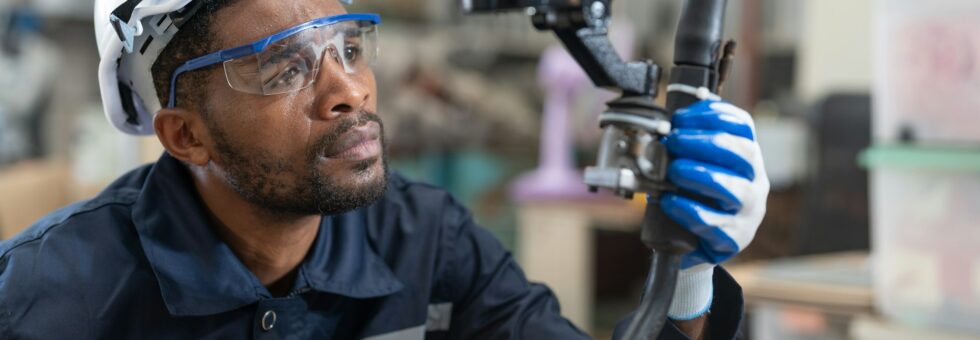 Black male engineer automation engineer checking head welding robot arm machine in factory