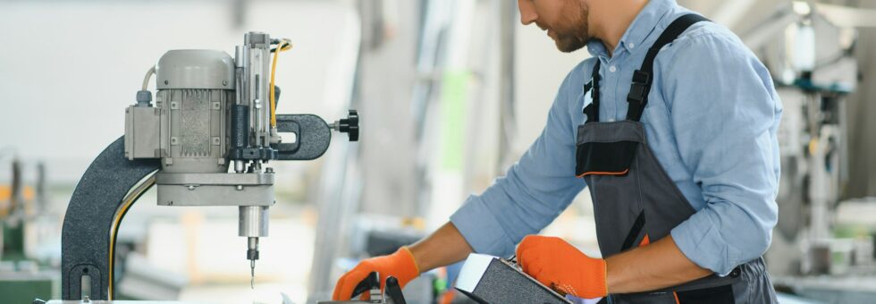 Male factory mechanics or Engineer in safety uniforms are working on metal drilling machines